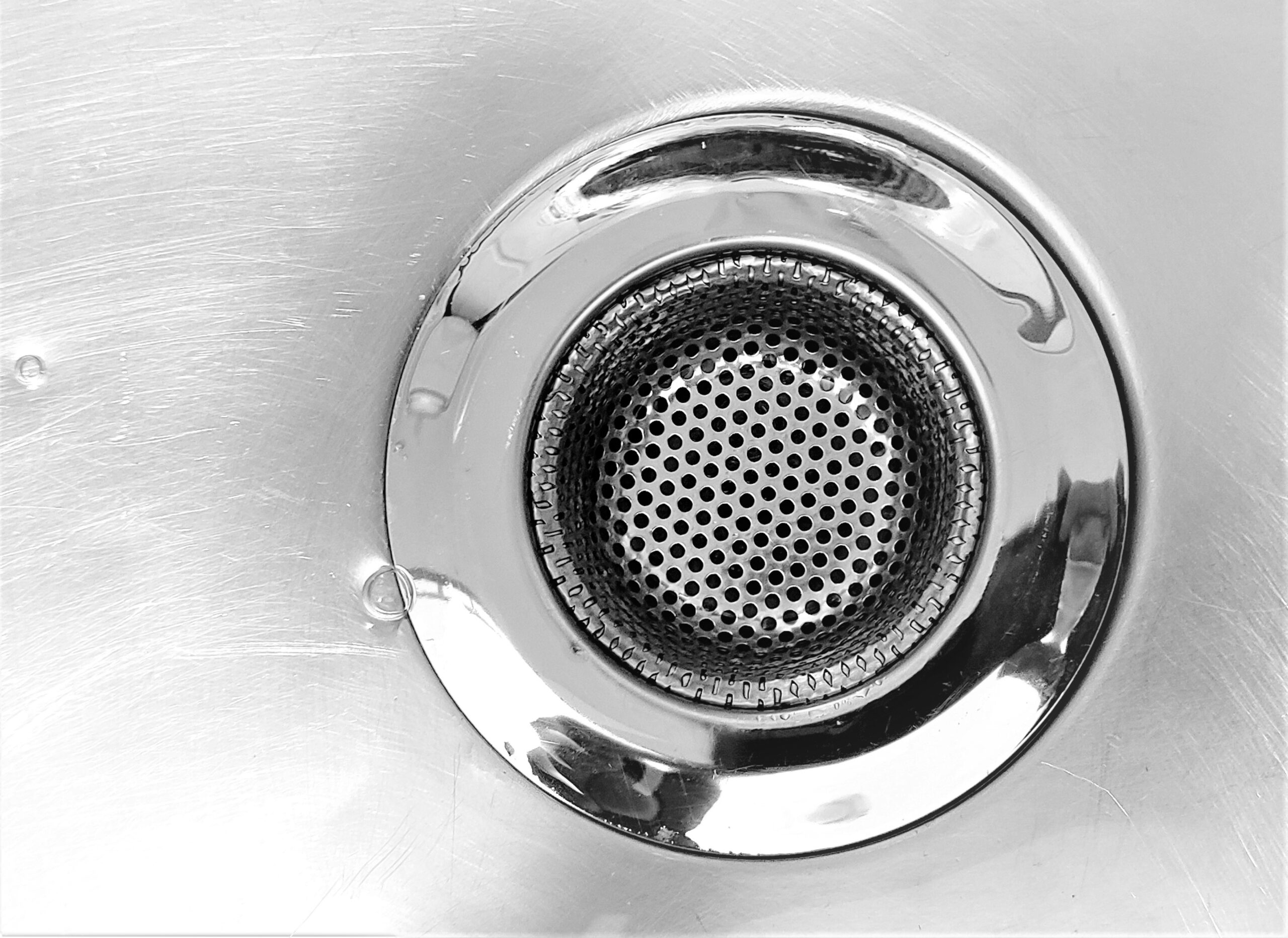 black and white close up photo of sink drain, garbage disposal