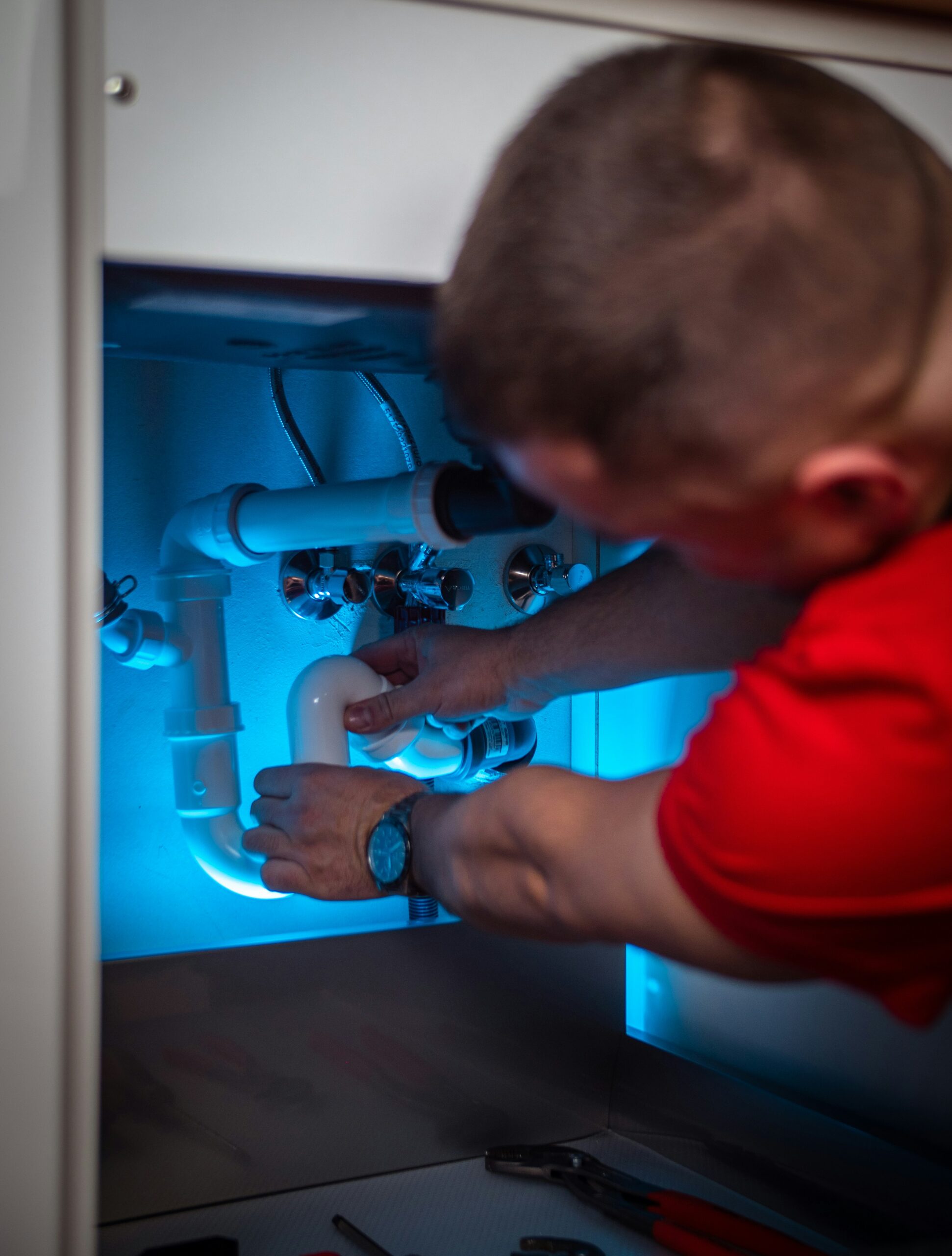 plumber working on pipes under sink